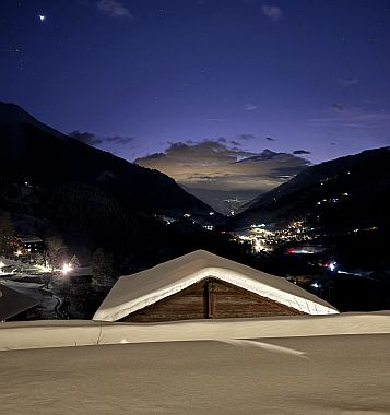 Foto einer nächtlichen Schnee-Weihnachtslandschaft mit belichteten Dörfern zwischen Bergen