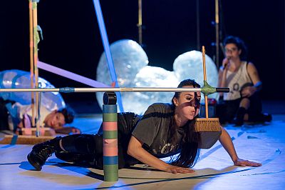 Eine Performerin pustet liegend einen Besen an (c)Fréderic Lovino